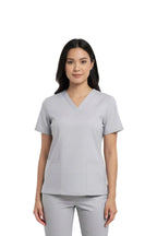 Woman wearing a gray scrub top on a white background